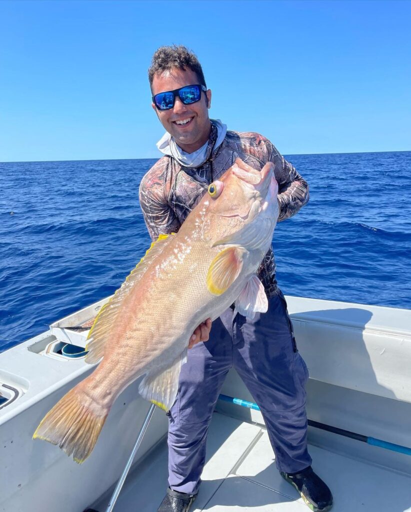 A cheerful angler holding a large Snapper caught on a deep sea fishing charter off the coast of Key West, showcasing the exceptional deep sea fishing packages offered in the region.